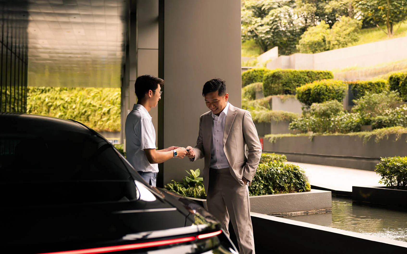 Man in a suit receiving car keys outdoors.