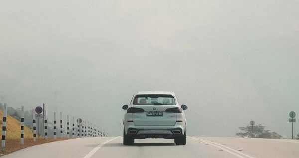 White SUV driving on a misty road.